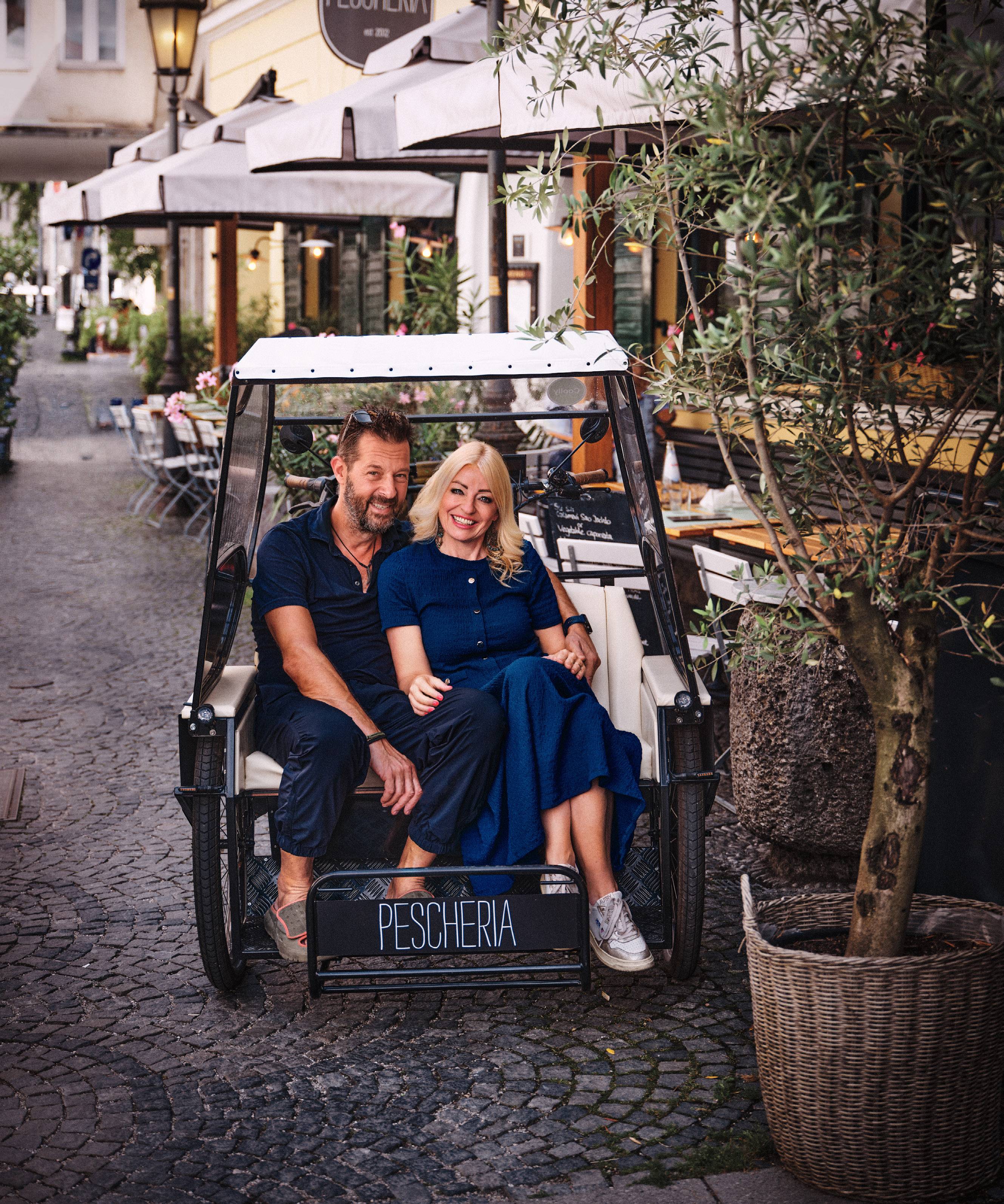 Pamela und Andre Bahlo in einer Rikscha vor der „Pescheria“ in München